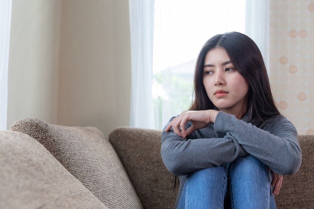 unhappy asian pretty young woman siting alone couch with feeling sadness