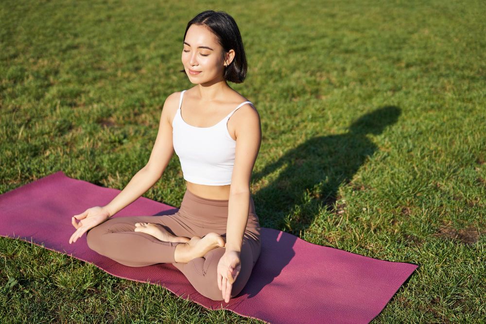 portrait smiling asian woman meditating doing yoga fresh air relaxing rubber mat